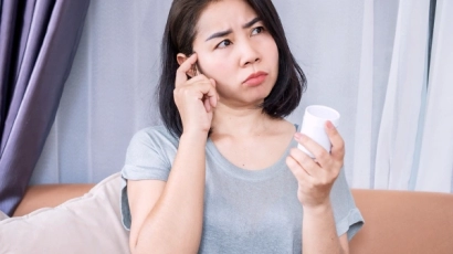 A woman holding a pill bottle in her right hand, wondering if she has taken her medicine. ADHD in women can result in such forgetfulness and absentmindedness
