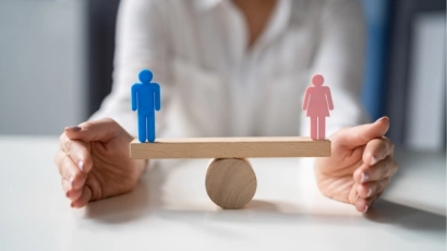 A balance scale with a blue wooden male figure on the left end, and a pink wooden figure on the right end, representing gender bias, which is one of the reasons ADHD in women is less commonly diagnosed