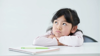 Girl with her head on her arms, looking towards the side with a dreamy expression. Inattentive ADHD in women can cause ADHD in women to be less commonly diagnosed