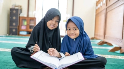 Two girls seated cross-legged on the floor with a book on their laps