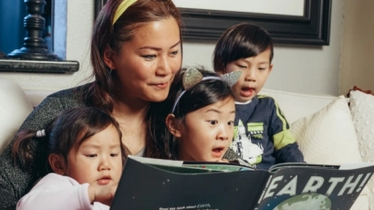 Mother reading kids' stories with her three children