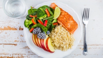 Plate of salmon, rice, broccoli and apples. Eating healthy meals can improve one's physical quotient
