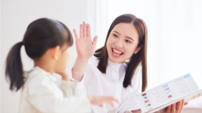 An asian teacher high-fiving a young girl after completing a worksheet. Special education schools (SPED) have specialised personnel, such as therapists, psychologists and social workers.