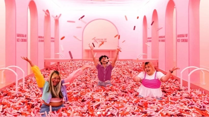 A family in a pink room, in a ball pit with inflatable pink sprinkles. The museum of ice cream is one of the best kid friendly activities in Singapore.