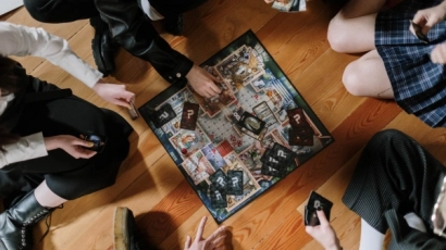 Family huddled around a board game. Celebrate Father's Day 2025 by having a family game night.