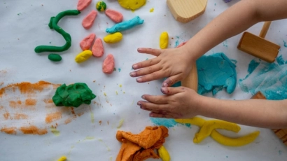 Hands kneading playdough into various shapes. Playdough is a form of sensory play for toddlers.