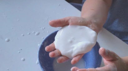 A hand cupping oobleck, which is an excellent form of sensory play for toddlers.