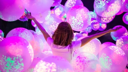 Girl with her hands outstretched, in front of glowing balloons at the balloon museum, which is a fun activity that kids can go for during the June Holidays