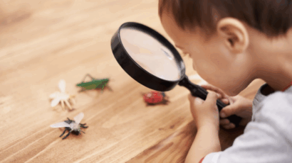 Little boy looking at toy bugs like an explorer, one of the fantasy play ideas suggested here